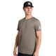 En mand iført en Saysky Clean Pace-T-shirt i taupe med et hvidt mærke på venstre ærme og en sort baseballkasket kigger til siden. Han står foran en ensfarvet hvid baggrund med højre arm afslappet ned langs siden.