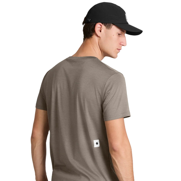 En person, der ses bagfra på en hvid baggrund, har en Saysky Clean Pace-T-shirt til mænd i farven taupe på, med et lille rektangulært mærke nederst på ryggen, samt en sort kasket.