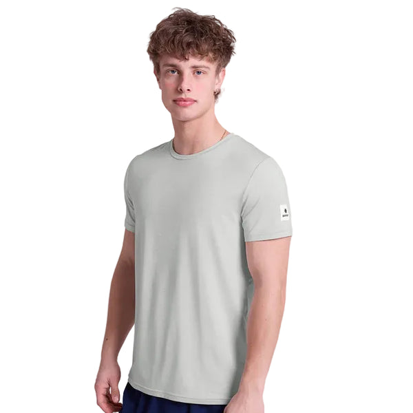 En ung mand med kort, krøllet hår kigger fremad iført Saysky Clean Pace T-shirt, Herre, Grey og mørke shorts. T-shirten har en lille logopatch på venstre ærme - ideel til træning - på en almindelig hvid baggrund.