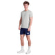 En mand ser frem for sig i en Saysky Clean Pace T-shirt, Herre, Grey, sammen med mørkeblå shorts, hvide strømper og hvide sneakers på en almindelig hvid baggrund.