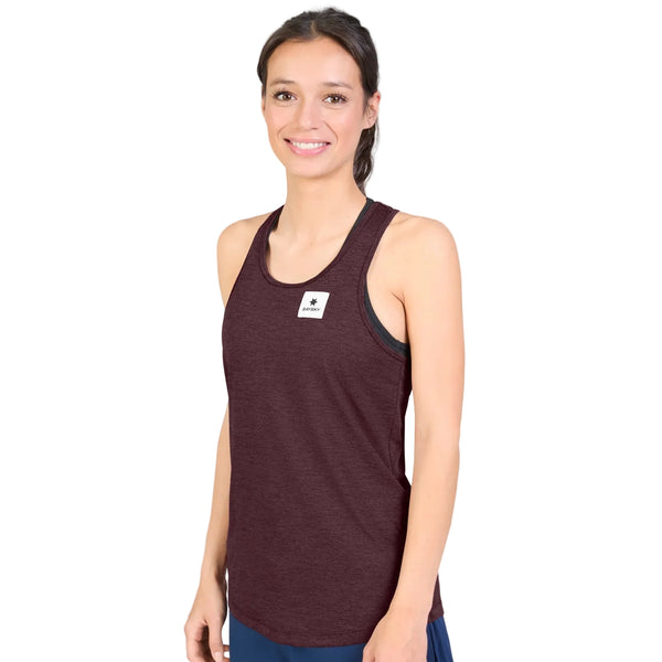 En kvinde med langt, brunt hår, der er sat op, iført en ærmeløs, burgunderfarvet Saysky W Clean Combat Pro Singlet til kvinder med et lille, hvidt, rektangulært mærke på brystet, står og smiler foran en ensfarvet hvid baggrund.