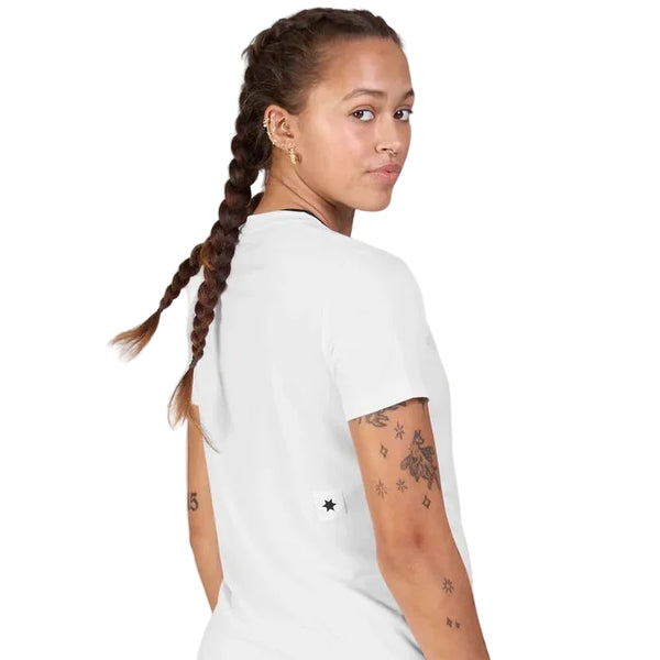 Man ser en person bagfra med langt brunt hår, sat op i to fletninger, som vender sig om og kigger over skulderen. Personen har en Saysky Clean Combat Pro T-shirt, Dame, hvid på – en T-shirt, der er kendt for sit hurtigtørrende materiale. På højre arm ses flere tatoveringer. Baggrunden er ensfarvet hvid.