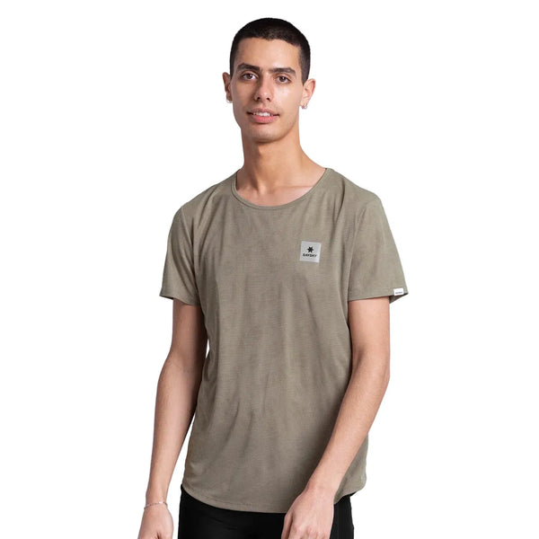En ung mand med kort mørkt hår er iført en Saysky Reactive Flow T-shirt, Herre, med en mørk beige logopatch på brystet, og står på en almindelig hvid baggrund.