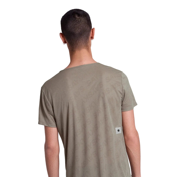 En person med kort mørkt hår ses bagfra iført en Saysky Reactive Flow T-shirt, Herre, Dark Beige Logo, med et lille rektangulært mærke nederst på ryggen mod en almindelig hvid baggrund.