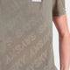 Nærbillede af en person iført Saysky Reactive Flow T-shirt til mænd med et diskret gittermønster, "SKY" med store, svage bogstaver og et mørkebeige logo. Kun den ene arm og en del af overkroppen er vist.