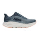 Et par Hoka Clifton 11 dame-løbesko i farvekombinationen Faded Navy / Glimmering Blue, med et blågråt sportsligt design med HOKA-logo på siden, maksimal stødabsorbering takket være den hvide, polstrede mellemsål og en let orange ydersål med en let struktur. Den lave silhuet fuldendes med snørelukning.