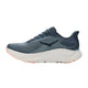 En Hoka Clifton 11 damesko i farvekombinationen Faded Navy / Glimmering Blue, med en blågrå overdel i mesh, der sikrer optimal åndbarhed, hvid sål og ferskenfarvede detaljer på ydersålen. Skoen er vist i profil vendt mod venstre med et stiliseret Hoka-logo på siden og tilbyder maksimal støddæmpning.