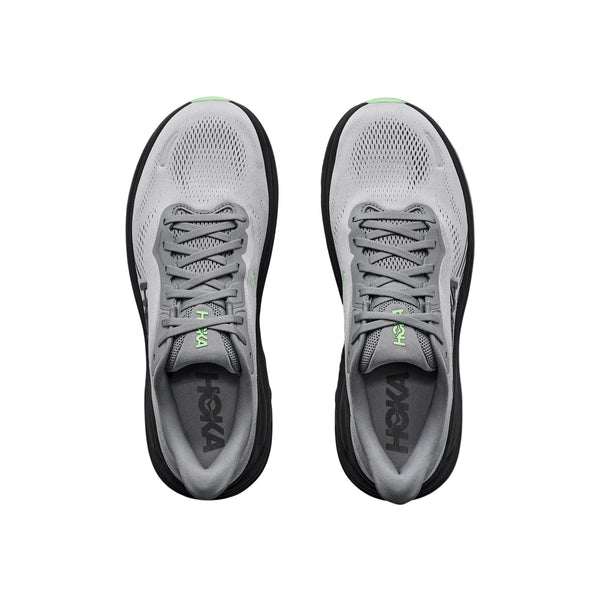 Oversigtsbillede af et par Hoka Clifton 11 herresko i farvekombinationen Galactic Grey / Stardust med sorte såler, lysegrønne detaljer på tungen og HOKA-logoet synligt på indersålerne. Skoene, der er kendt for deres optimale stødabsorbering, står side om side på en hvid baggrund.