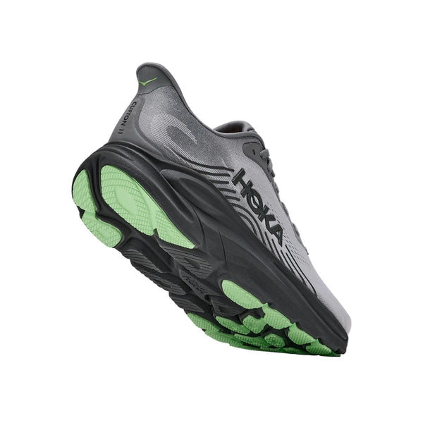 Et par Hoka Clifton 11 herreløbesko i farven Galactic Grey / Stardust med HOKA-logo på siden er vinklet, så den grønne sål og mellemsålen med maksimal støddæmpning fremhæves på en hvid baggrund.