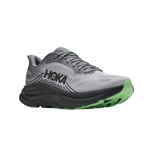 Et par Hoka Clifton 11 herreløbesko i farven Galactic Grey / Stardust, med sort HOKA-logo, en sort mellemsål og grønne detaljer på ydersålen for maksimal støddæmpning, er afbildet i en trekvartvinkel på en hvid baggrund.