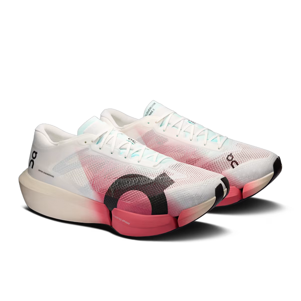 Et par On Cloudboom Strike 2 unisex-løbesko i farvekombinationen hvid/kamelia, med en tyk, buet sål med integreret Carbon Speedboard, sorte detaljer og On-logoet synligt på siden og tungen – ideelle som konkurrencesko eller maratonsko – præsenteret på en ensfarvet hvid baggrund.