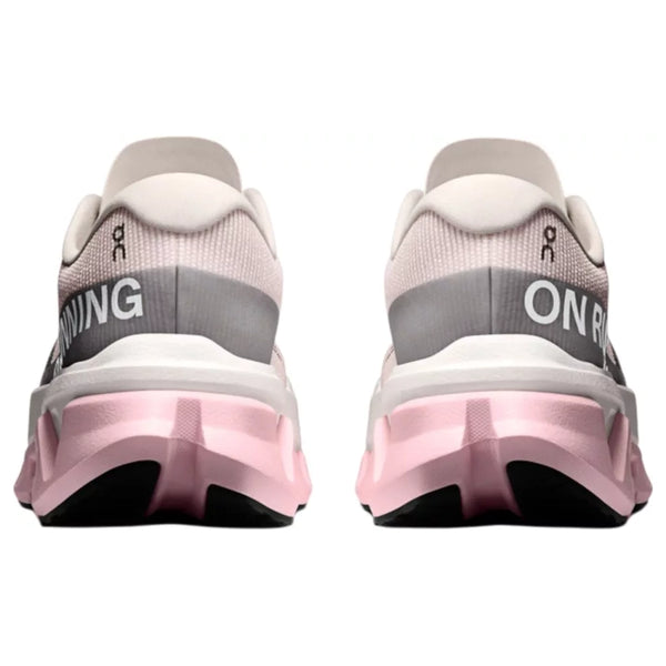 On Cloudmonster 3 Hyper løbesko dame i Ivory/Peony har lyserød og hvid overdel, grå hælpartier med "ON RUNNING" og lyserød-sorte såler for maksimal dæmpning. Vist fra bagsiden.