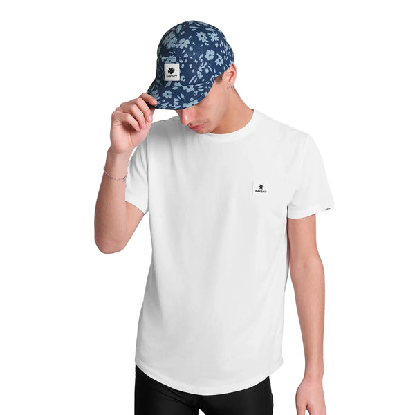 En person i en almindelig hvid, fugttransporterende T-shirt med et lille logo og Saysky Combat Cap, Unisex, Blue Flower, der kigger ned og holder på randen - perfekt udstyr til løb.
