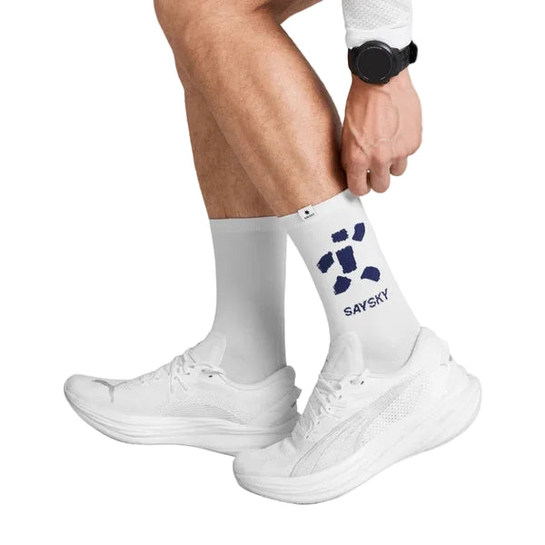 En person, der har hvide løbesko på og et par Saysky Combat High Socks, unisex, Checks Of Edo med et blåt SAYSKY-logo, retter på sin sok. Personen bærer desuden et sort armbåndsur. Baggrunden er ensfarvet hvid.