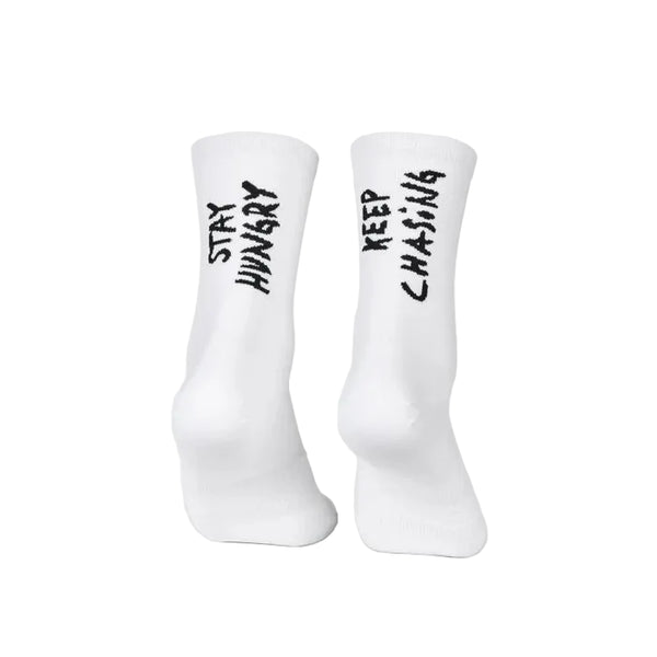 Her er din omskrevne sætning: To hvide Saysky Combat High Socks, unisex, Stay Hungry, vises stående. Den venstre strømpe har teksten »STAY HUNGRY« i sort, mens den højre har teksten »KEEP CHASING« i sort – begge tekster er trykt lodret. Disse unisex-træningsstrømper er de perfekte performance-strømper til din næste træning.
