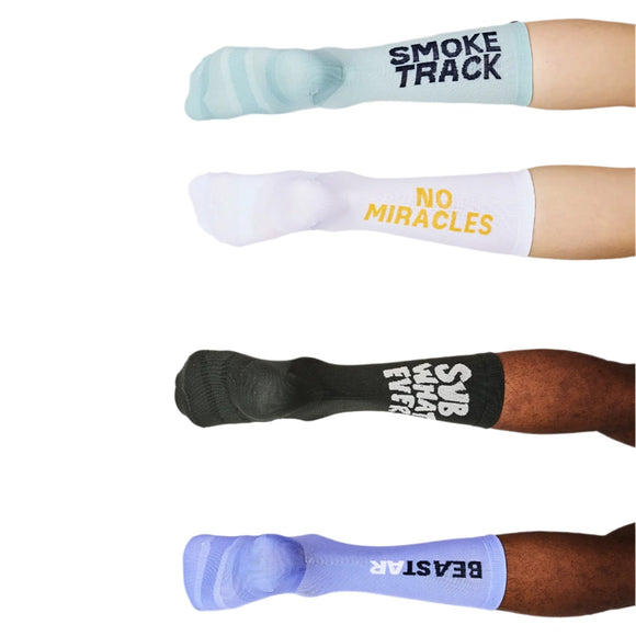 Fire ben i forskellige Saysky Statement Combat Socks 100: lyseblå med SMOKE TRACK, hvid med NO MIRACLES i gul, sort med SUB WHAT EVER og lavendel med BEASTAR - alle med optimal støtte og maksimal ydeevne.