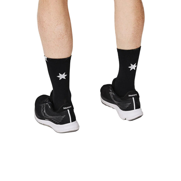 En person iført sorte Saucony-løbesko og sorte Saysky Combat High Socks 100 med en hvid ottetakket stjerne på ryggen, fotograferet bagfra, så man kun kan se underben og fødder.