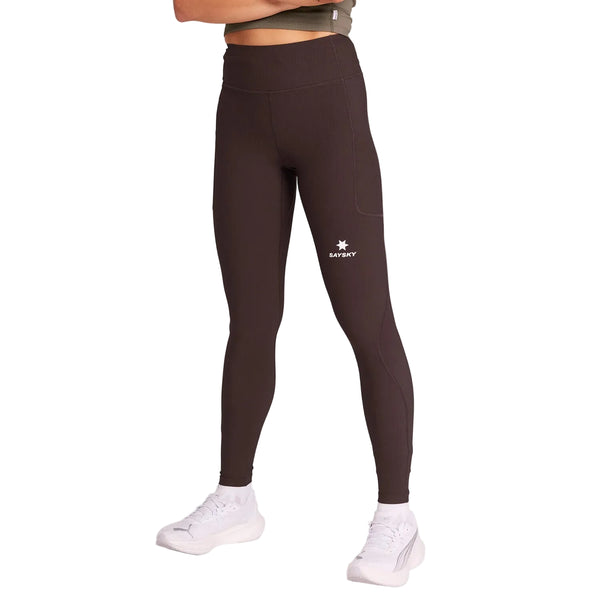 En person iført Saysky Combat+ Rib Long Tights, Dame, Coffee - mørkfarvede, højtaljede tights med et lille hvidt logo på venstre lår - sammen med hvide sneakers. Overkroppen er delvist ude af billedet.