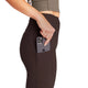 En person iført Saysky Combat+ Rib Long Tights, Dame, Coffee og en olivengrøn top lægger en sølvfarvet iPhone i sidelommen på leggingsene. Billedet er beskåret, så det kun viser overkroppen og overbenene.