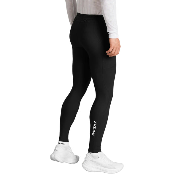 En person iført sorte Saysky Combat+ Rib Long Tights, Herre, fremstillet af åndbart ribstof, en hvid langærmet trøje og hvide løbesko står med ryggen til kameraet foran en ensfarvet hvid baggrund.