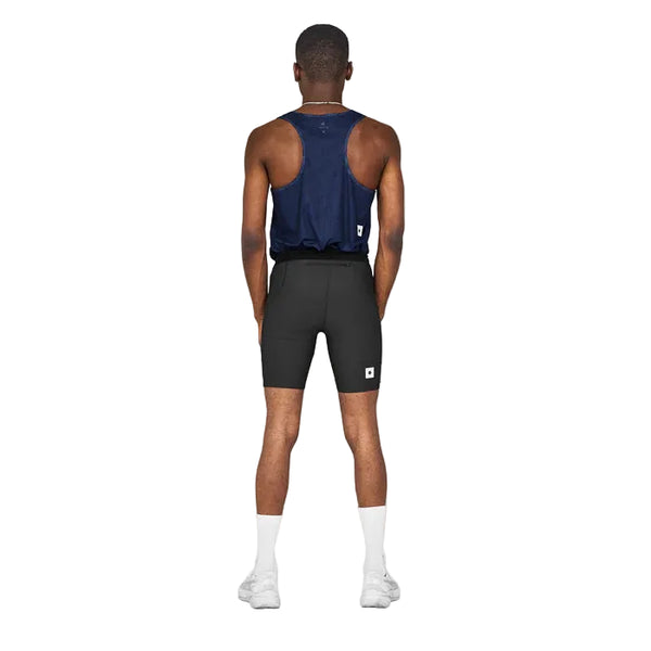 En person står med front mod kameraet iført en marineblå ærmeløs top og Saysky Combat+ Rib Running Short Tights 8, Herre, Black, med hvide sokker og sportssko på en almindelig hvid baggrund.