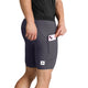 En person, der har mørkegrå Combat+ Rib Short Tights 8″ fra Saysky på – en model til mænd med en praktisk lomme til mobiltelefonen – putter en lyserød smartphone ned i lommen. Kun den nederste del af kroppen og lårene ses på den hvide baggrund.