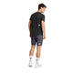 En mand står med ryggen til og er iført en sort T-shirt, et par grå Saysky Combat+ Rib Short Tights 8″ til mænd, hvide sokker med en sort stjerne og hvide sneakers. Hvert stykke tøj er forsynet med det lille, hvide, firkantede Saysky-logo. Baggrunden er ensfarvet hvid.
