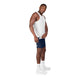 En mand står foran en hvid baggrund iført en hvid ærmeløs T-shirt, Saysky Combat+ Rib Short Tights 8″ Herre i blå, hvide strømper med rund tå og hvide sportssko. Han kigger let mod venstre, mens han med højre hånd holder fast i sin T-shirt.