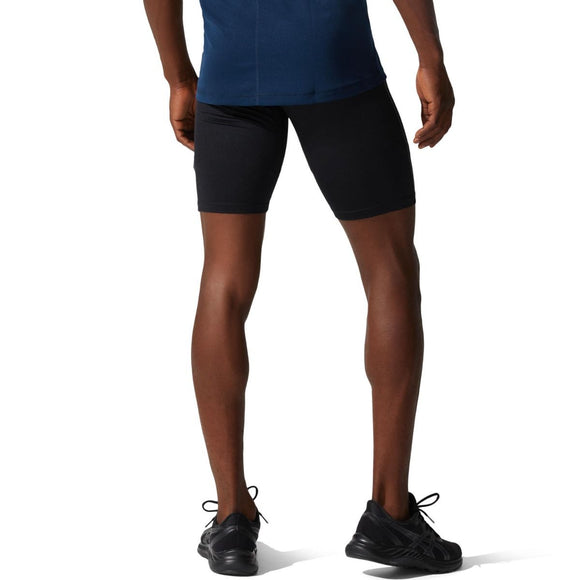 En person står med ryggen til og er iført en blå trøje, Asics Core Sprinter Short Tights Herre i sort og sorte sportssko. Kun underkroppen og benene er synlige, med armene afslappet i siden.