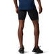 En person står med ryggen til og er iført en blå trøje, Asics Core Sprinter Short Tights Herre i sort og sorte sportssko. Kun underkroppen og benene er synlige, med armene afslappet i siden.