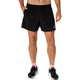 Der ses en person fra livet og ned på en hvid baggrund, iført ASICS Core 5In Shorts, Herre, Performance Black, en sort T-shirt, sort-hvide sportssko og lyserøde sokker.