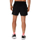 En mand står med ryggen til kameraet iført ASICS Core 5In Shorts Herre i farven Performance Black, sorte og hvide løbesko samt lyserøde sokker foran en ensfarvet hvid baggrund.