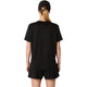En person med langt blondt hår sat op i en hestehale har en sort kasket på, en Asics Core SS Top, Dame, Performance Black, samt sorte shorts, og står med ryggen til kameraet foran en ensfarvet hvid baggrund.