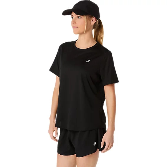 En kvinde iført ASICS Core Ss Top, Dame, i farven Performance Black står let vendt til siden foran en ensfarvet hvid baggrund. Hun har kombineret toppen med matchende sorte shorts og en sort kasket. Både toppen og shortsene er forsynet med et lille hvidt ASICS-logo.