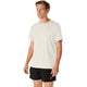 En mand står foran en ensfarvet hvid baggrund iført en ASICS Core SS Top, Herre, i farven creme samt sorte sportsshorts. Begge beklædningsgenstande er forsynet med små ASICS-logoer. Han kigger let til siden med et neutralt udtryk i ansigtet.
