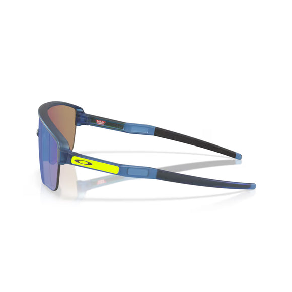 Oakley Corridor SQ unisex sportsbriller i mat transblå med Prizm Sapphire-linser vises fra en sidevinkel med et gult Oakley-logo på armen mod en hvid baggrund.
