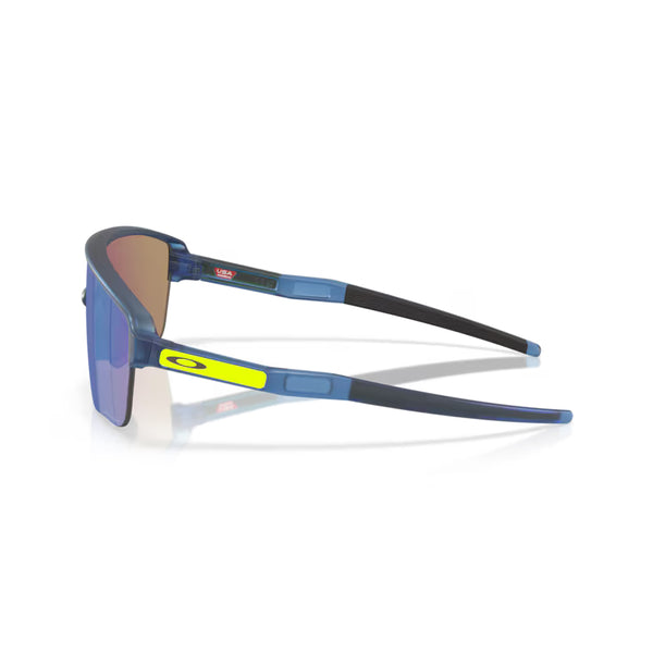 Oakley Corridor SQ unisex sportsbriller i mat transblå med Prizm Sapphire-linser vises fra en sidevinkel med et gult Oakley-logo på armen mod en hvid baggrund.