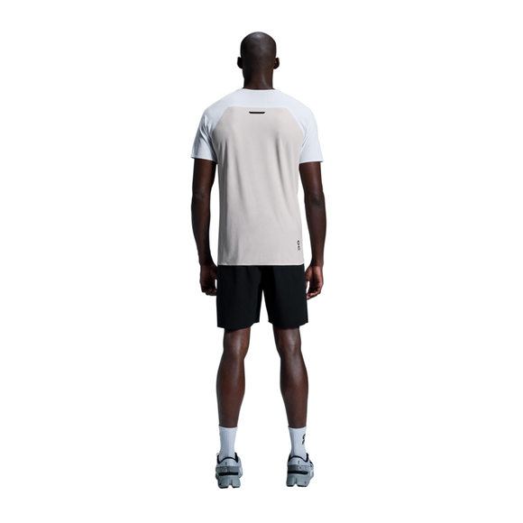 En mand står med ansigtet vendt mod kameraet iført en On Performance-T Herre i hvid/sølv, sorte shorts, hvide sokker og grå sneakers på en hvid baggrund.