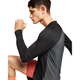 En mand iført en On Performance Long-T, Herre, Black/Eclipse og røde shorts knæler med en bøjet arm og kigger fremad mod en hvid baggrund.