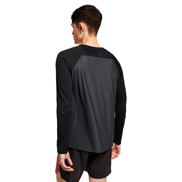 En mand ser væk, iført On Performance Long-T til mænd i Black/Eclipse og sorte shorts med rødt sidepanel, og står på en almindelig hvid baggrund.