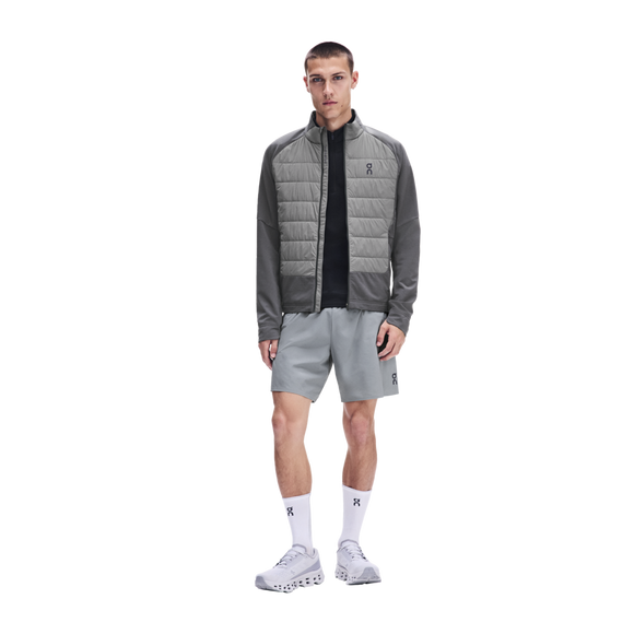 En mand iført en On Weather Hybrid-jakke, Herre, Eclipse/Ember, grå sportsshorts, hvide sokker og lyse sneakers.