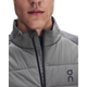 Nærbillede af en person iført en Eclipse/Ember On Weather Hybrid-jakke, Herre, der er udført i et gråt, vind- og vandafvisende, isoleret design med krave med lynlås og et logo på brystet.