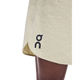 Nærbillede af den nederste del af ON Performance Volt Shorts, Herre, Hare i lys beige med et lille sort ON-logo i nederkanten, båret af en person med mørk hud.