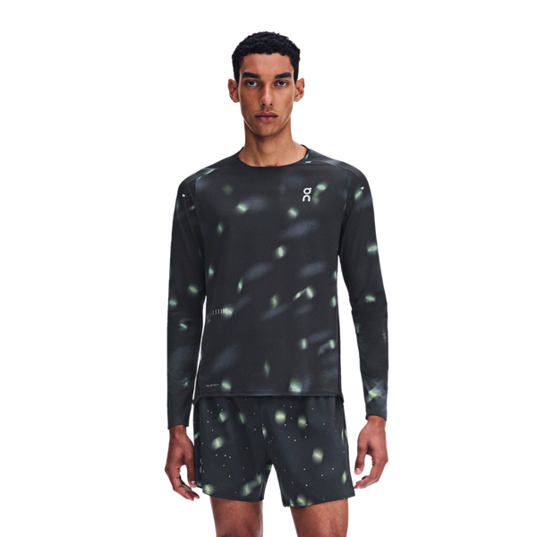 En mand iført en Performance Long-T Lumos 3, Herre, sort sportstrøje og matchende shorts med reflekterende lysmønstre som detaljer.