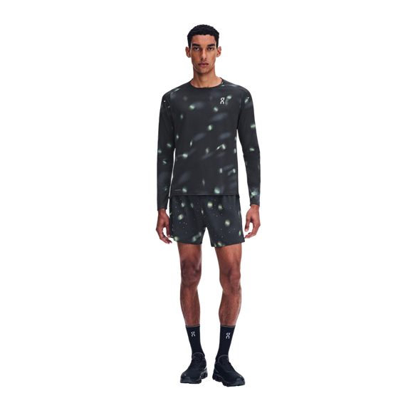 En mand iført en sort Performance Long-T Lumos 3, Herre, med langærmet skjorte og matchende shorts, begge med et reflekterende mønster med små lyspletter.