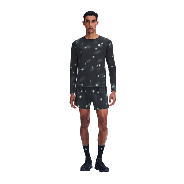 En mand iført en sort Performance Long-T Lumos 3, Herre, med langærmet skjorte og matchende shorts, begge med et reflekterende mønster med små lyspletter.