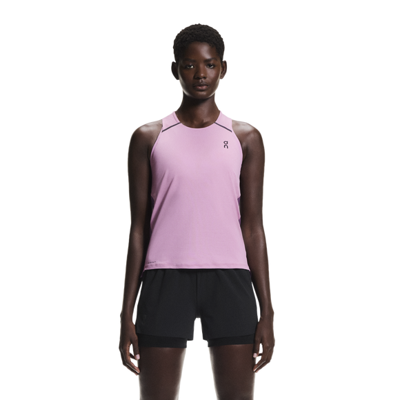 En person står med ansigtet fremad og er iført en On Performance Tank, Dame, Sakura/Dewberry med et lille logo på venstre bryst og sorte shorts på en almindelig hvid baggrund.