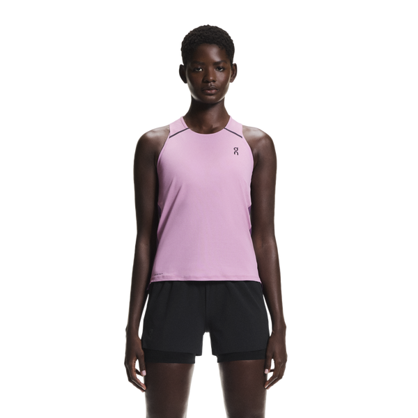 En person står med ansigtet fremad og er iført en On Performance Tank, Dame, Sakura/Dewberry med et lille logo på venstre bryst og sorte shorts på en almindelig hvid baggrund.