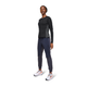 En kvinde kigger fremad iført On Performance Long-T, Dame, Black/Eclipse, sammen med mørke joggings og hvide løbesko med orange detaljer - ideel træningstøj dame - mod en almindelig hvid baggrund.