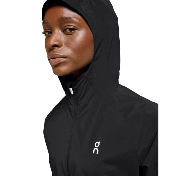 En kvinde iført On Core Jacket, Dame, Black med et lille hvidt logo på brystet, kigger lidt til siden mod en almindelig hvid baggrund.